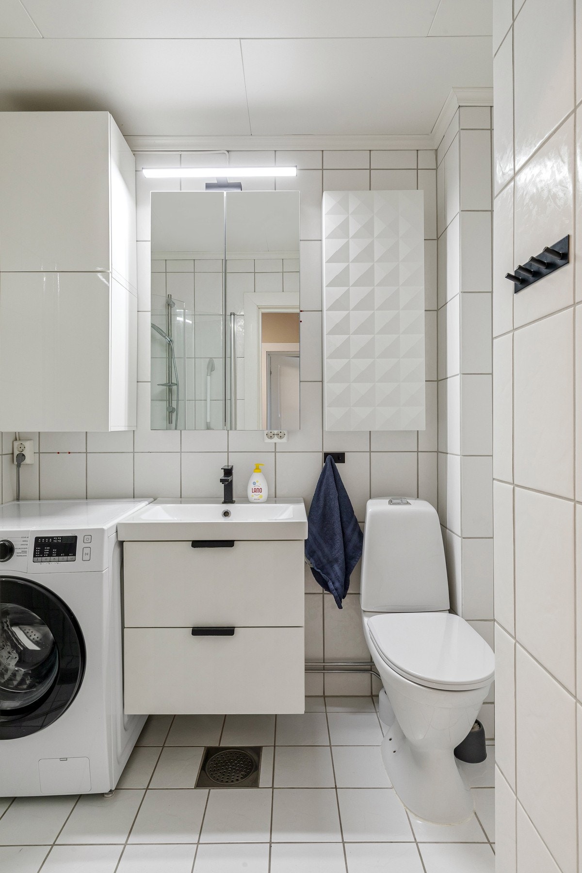 Badet fremstår som lyst og praktisk, med flislagte overflater og plass til vaskemaskin. Galleribilde