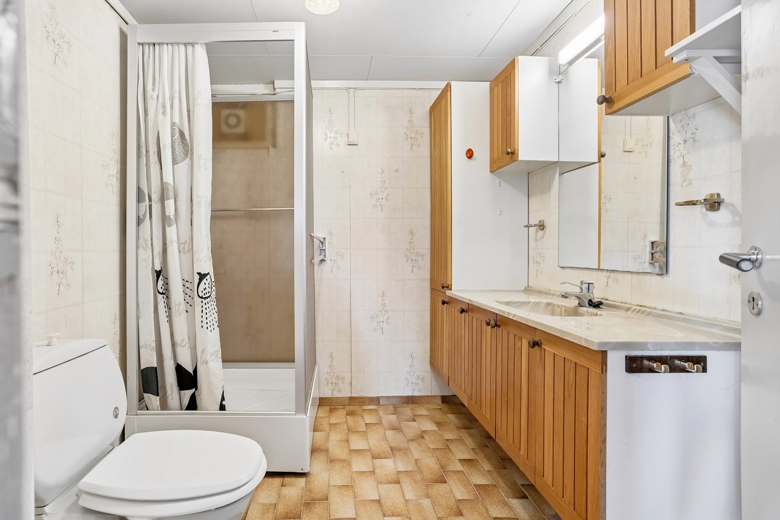 Badet i boligen ligger i underetasjen og er innredet med wc, dusjkabinett, hylleseksjon og servant med speil over Galleribilde