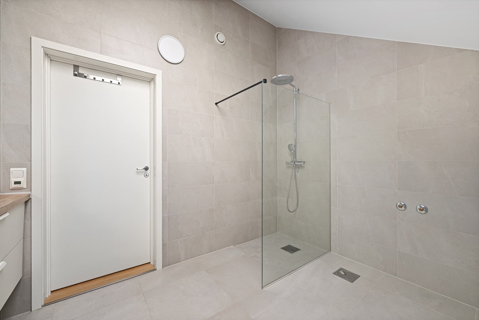 Romslig dusjsone med glassvegg. Badet har balansert ventilasjon med avtrekk i vegg. Galleribilde