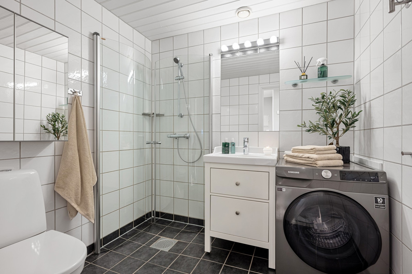 Flislagt bad med gulvvarme, dusjhjørne, toalett og opplegg for vaskemaskin. Badet er fra ca. 2003. Galleribilde