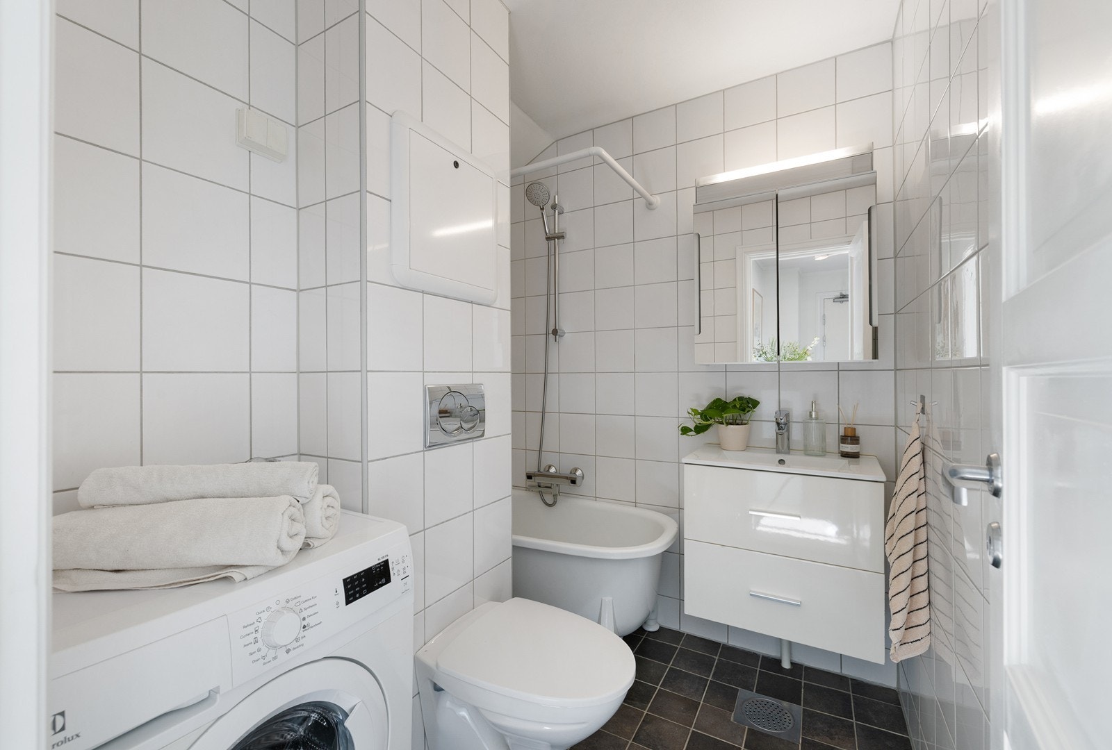 Flislagt bad fra 2013 med badekar, servantinnredning, speil og opplegg for vaskemaskin Galleribilde