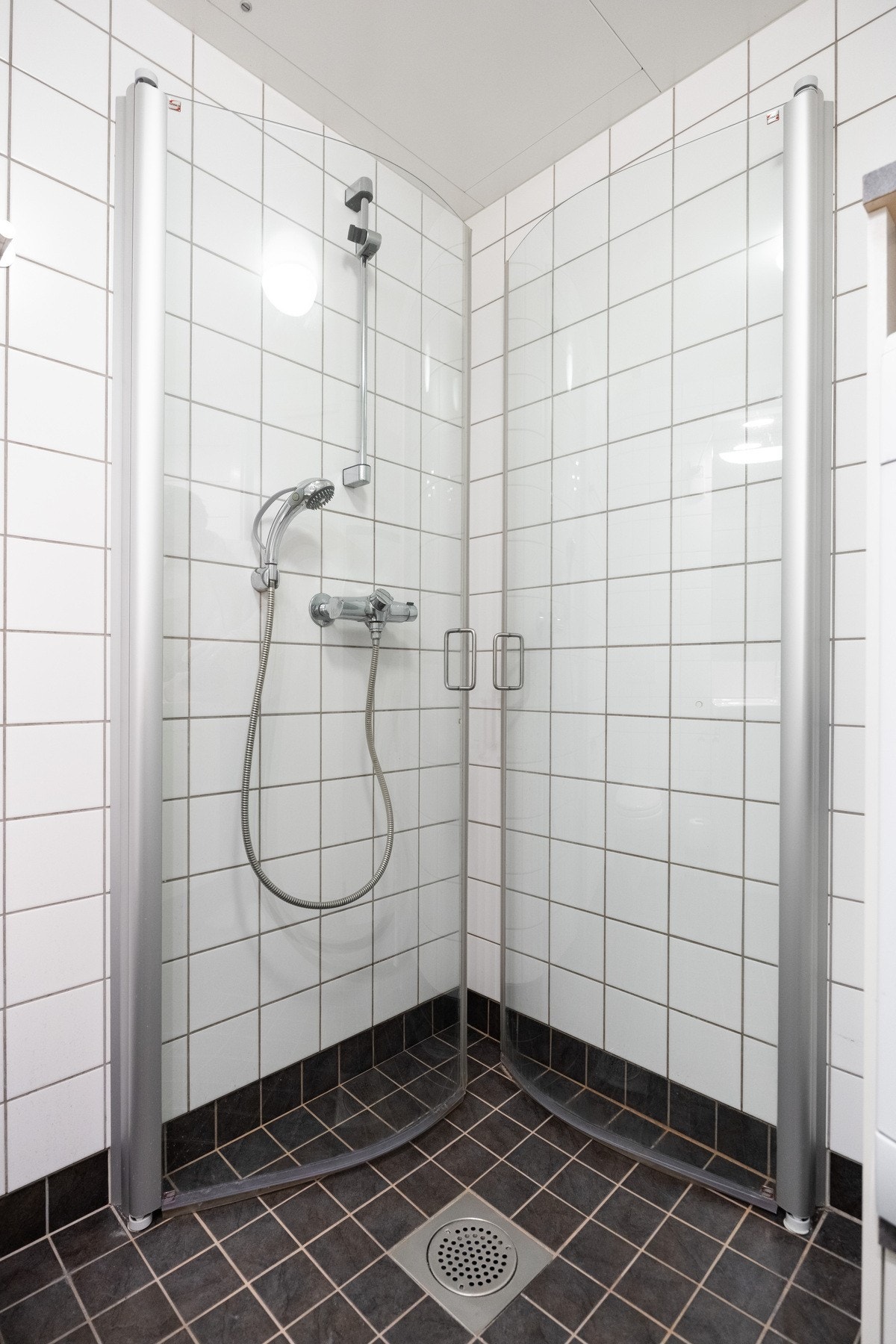 Badet er innredet med vegghengt servantinnredning, ovenpåliggende servant med armatur, speil med overlys og stikkontakt over servant, dusjhjørne med dører og vegghengt dusjarmatur, samt vegghengt toalett. Galleribilde