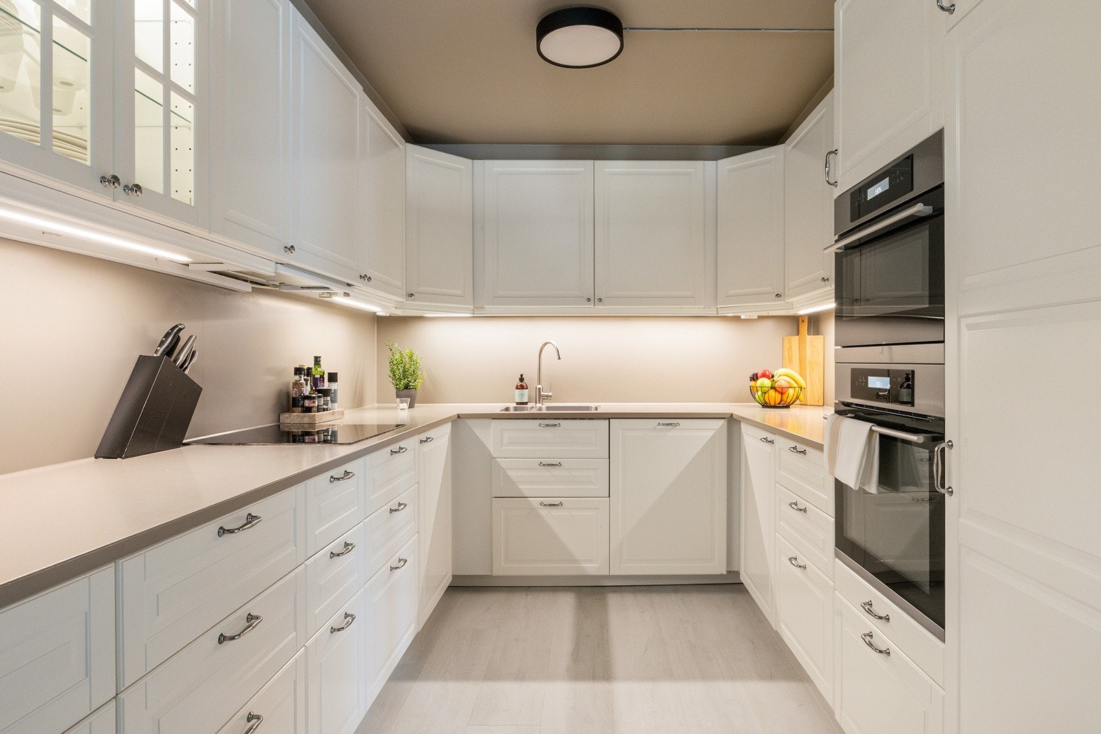 Kjøkkeninnredning med 1-speils profilerte fabrikklakkerte fronter, 4 stk. fronter m/glass, malt benkeplate og underlimt 1 1/2 oppvaskkum. Galleribilde