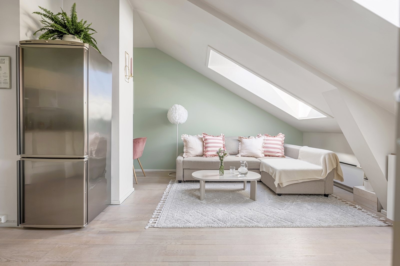 Leilighetens loftspreg forsterkes av de skrå takflatene og flere takvinduer som slipper inn rikelig med naturlig lys i oppholdsrommet. Galleribilde