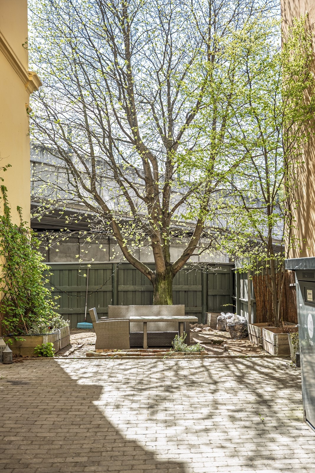 Pent opparbeidet bakgård med steinbelagt uteplass, sittegruppe og sykkelstativ. Galleribilde