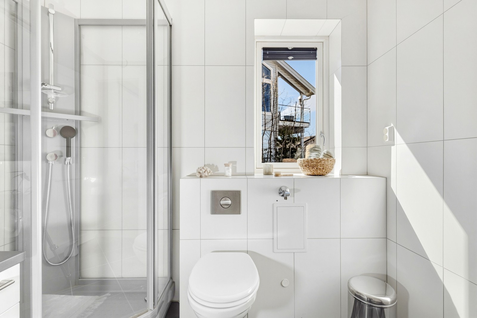 Badet er innredet med vegghengt klosett, dusjkabinett, og servant med innredning. Galleribilde