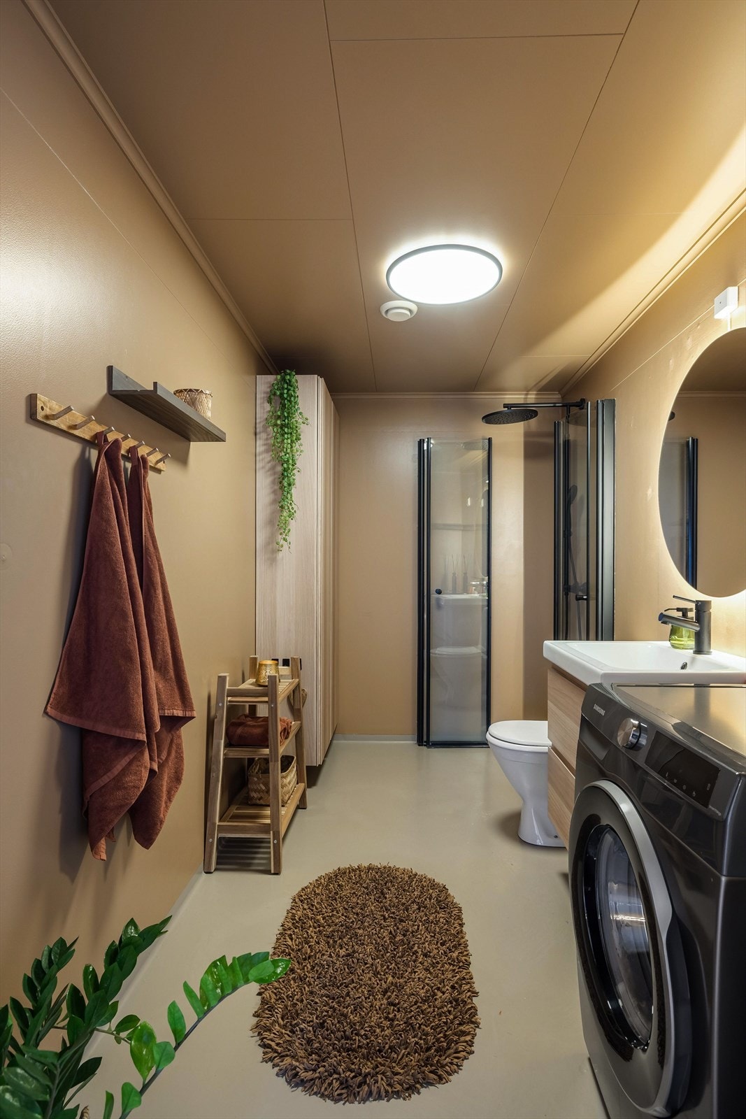 På badet er det varmekabler i gulvet, dushjørne, avtrekk over dusjen og opplegg til vaskemaskin. Ellers er det gulvmontert toalett og baderomsinnredning med heldekkende servant. Galleribilde