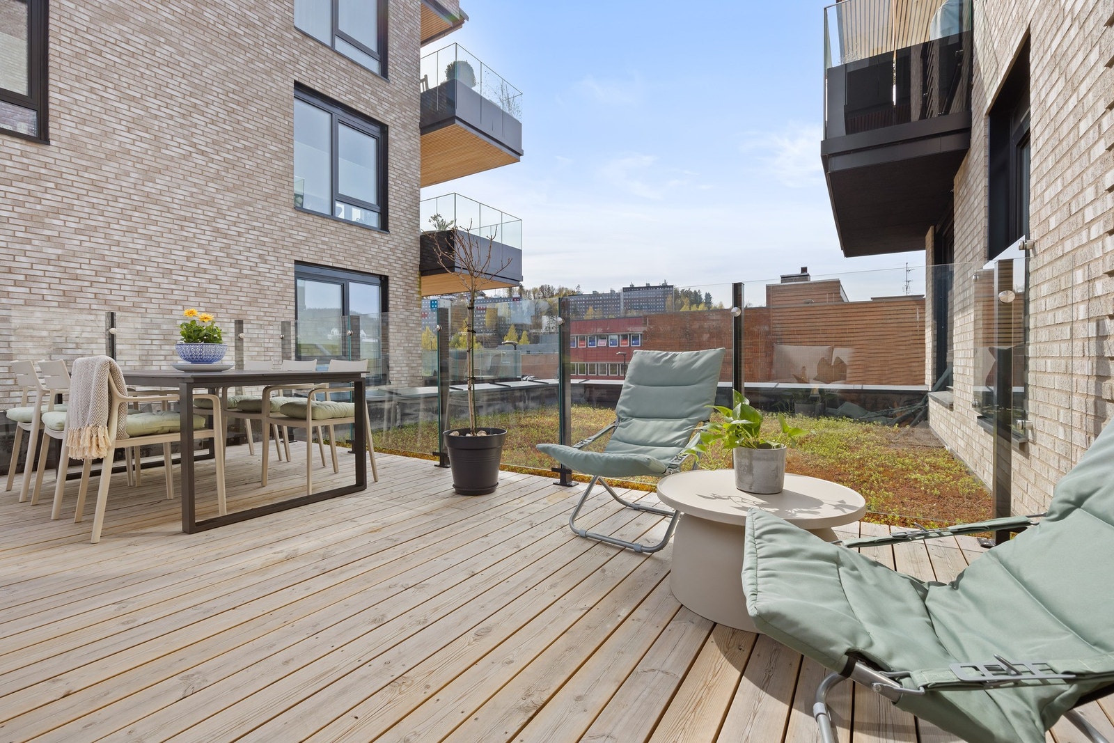 Lys og romslig terrasse med glassrekkverk, tilknyttet moderne leilighet i et urbant område. Galleribilde