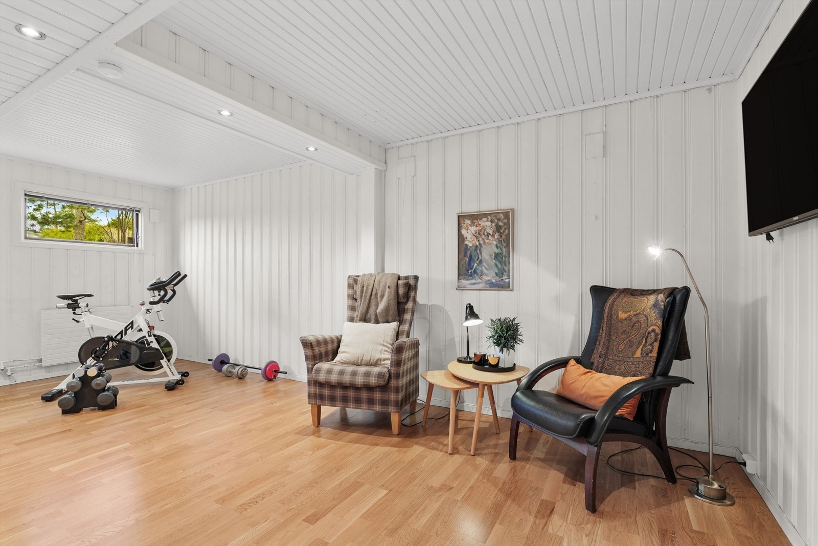 Stuen i 1.etasje har parkett på gulv og malt panel på vegg - og den egner seg godt som lekerom eller familiens kinorom Galleribilde