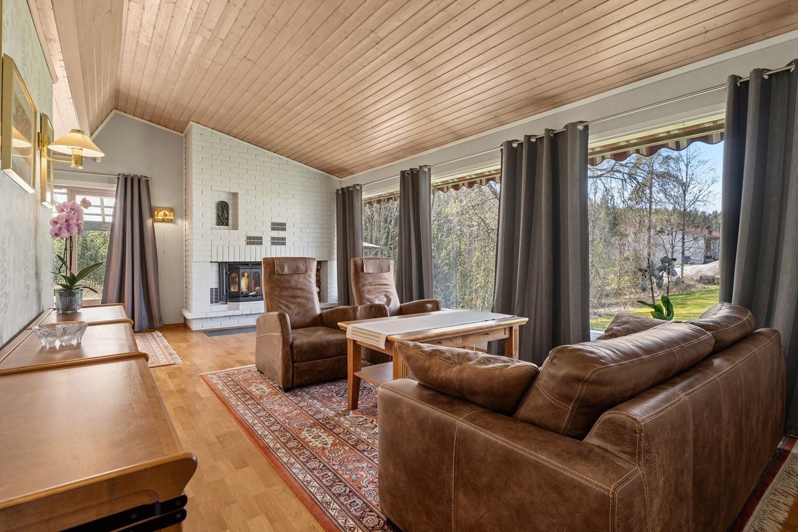 En peis med innsats i stuen gir lun varme på kalde dager. Legg merke til de store vindusflatene. Galleribilde
