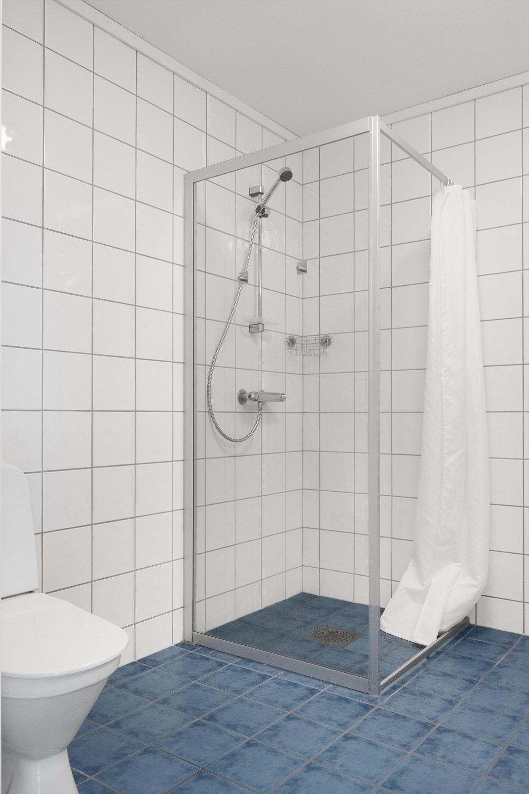 Badet har dusjhjørne med glassvegg og dusjforheng. Galleribilde