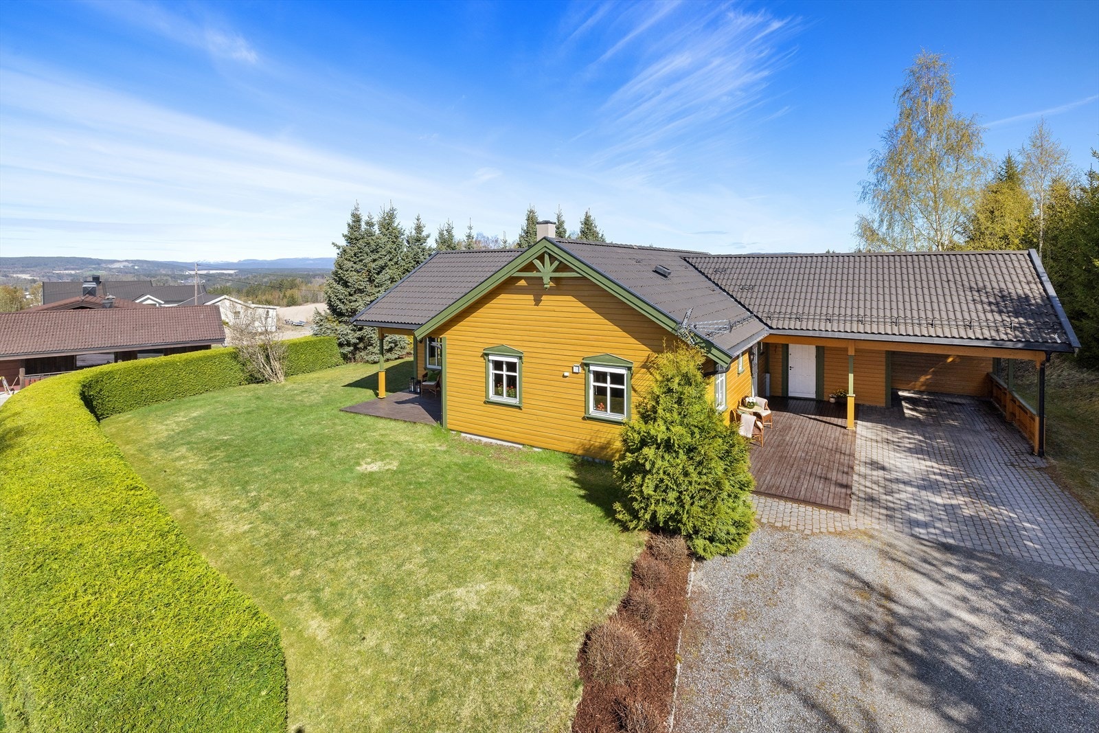 Boligen har en romslig carport med takoverbygg som strekker seg helt frem til inngangspartiet, og en pent opparbeidet hage. Galleribilde