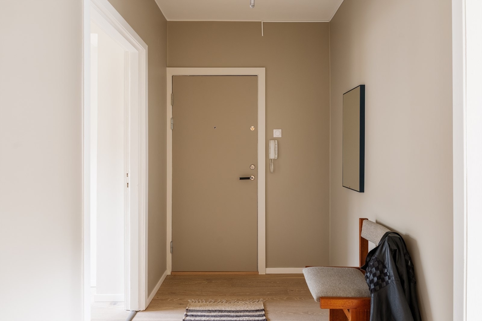 Entréen fremstår ryddig og funksjonell med beige vegger, hvite detaljer og lyst tregulv. Galleribilde