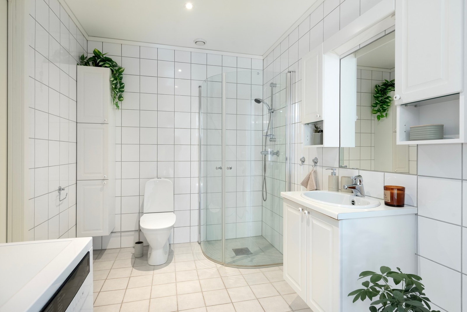 Fint bad/vaskerom med fliser på vegg og gulv, gulvvarme, og opplegg for vaskemaskin. Galleribilde