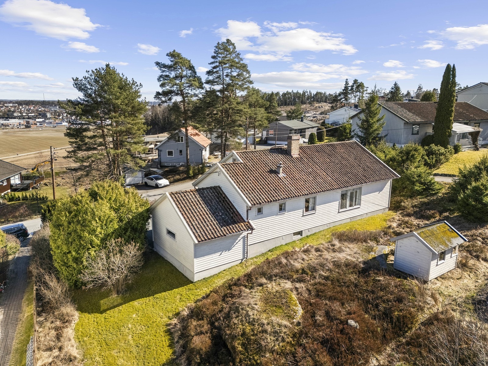 Eiendommen sett fra luften, som viser plasseringen i terrenget og nabobebyggelsen. Galleribilde