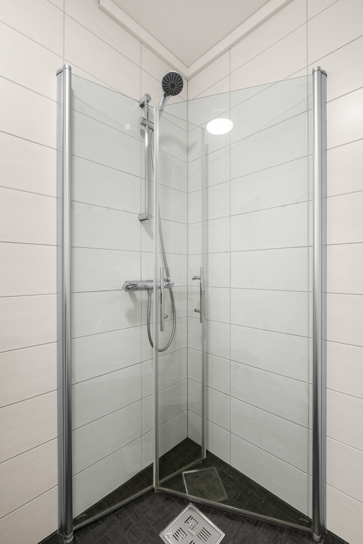 Badet er utstyrt med dusjhjørne med 2 stk. innfellbare dusjdører, servantinnredning, speilskap med integrert belysning og opplegg for vaskemaskin Galleribilde