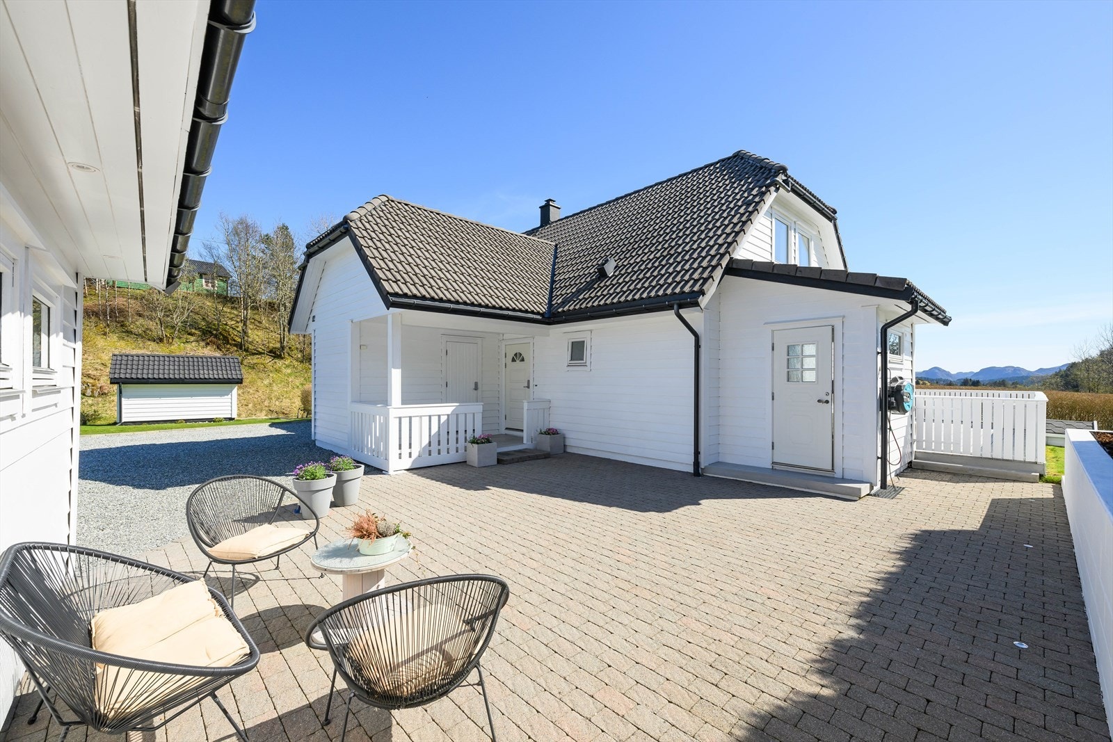 Stor brosteinsbelagt uteområde mellom huset og garasje. Galleribilde