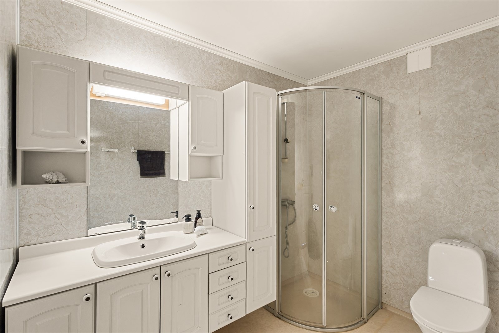Badet er innredet med baderomsinnredning med servant. toalett og dusj. Det er våtromsbelegg på gulv og baderomsplater på vegger. Galleribilde