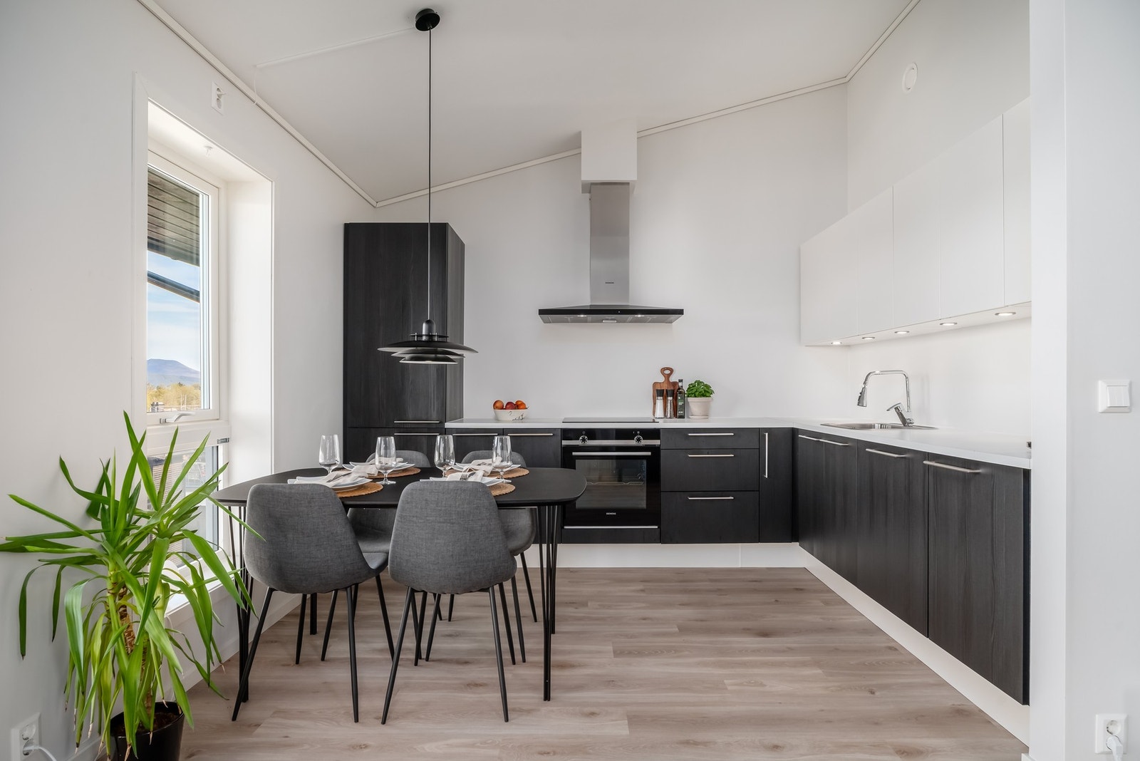 Flott kjøkken fra kvalitetsleverandøren HTH med mørke, glatte fronter og benkeplate av laminat. Legg merke til benkebelysningen i overskapene. Galleribilde