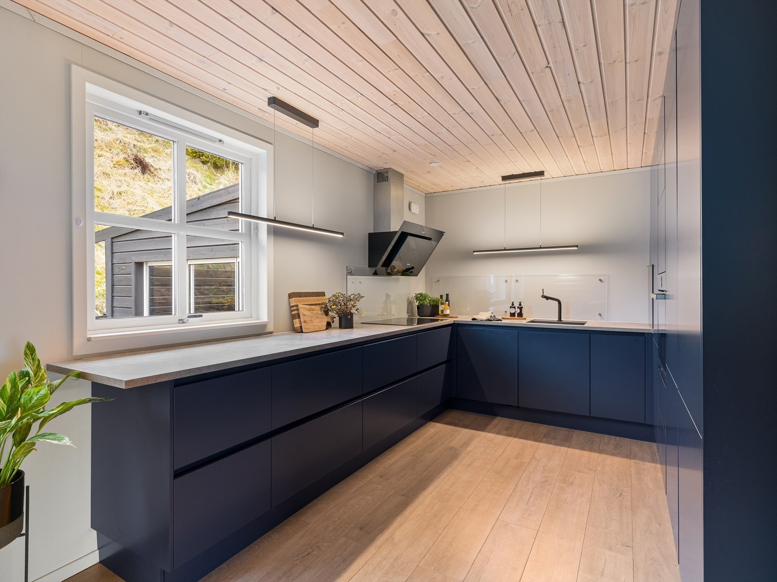 Kjøkkeninnredningen har slette, mørke fronter og benkeplater i laminert spon. Kjøkkenventilator med avtrekk rett ut. Galleribilde