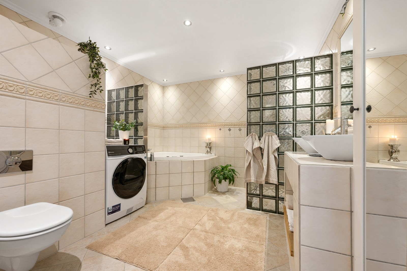 Badet i underetasjen er flislagt og utstyrt med både hjørnebadekar og dusjnisje med glassbyggestein. Galleribilde