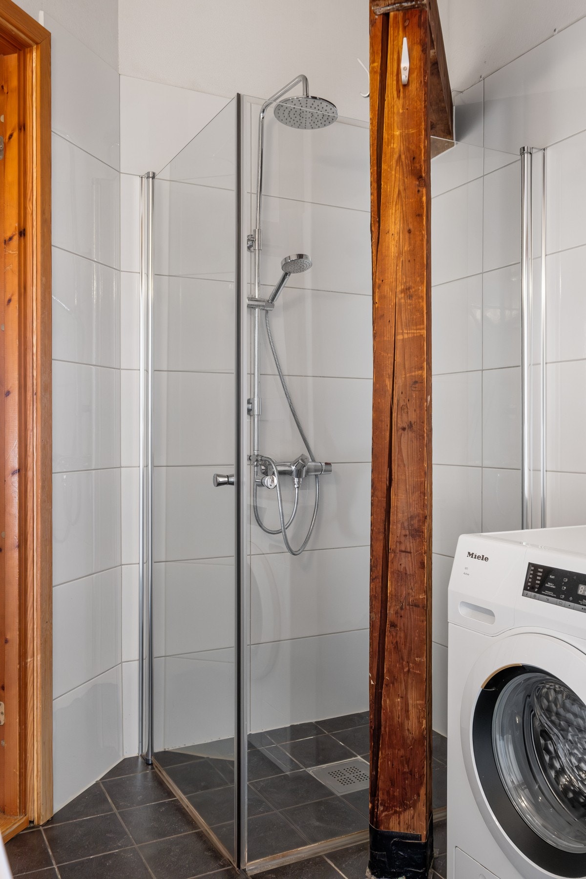 Badet er innredet med vegghengt toalett, dobbel servant, dusjhjørne med svingbare glassvegger og opplegg for vaskemaskin. Galleribilde