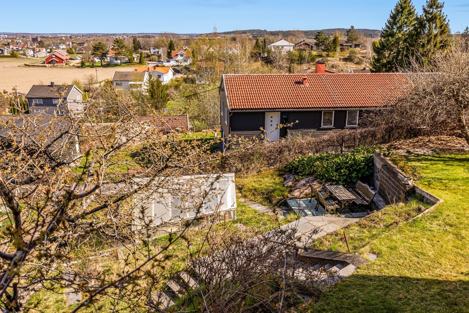 Den skrånende tomten er pent opparbeidet med flere nivåer og beplantning. Galleribilde