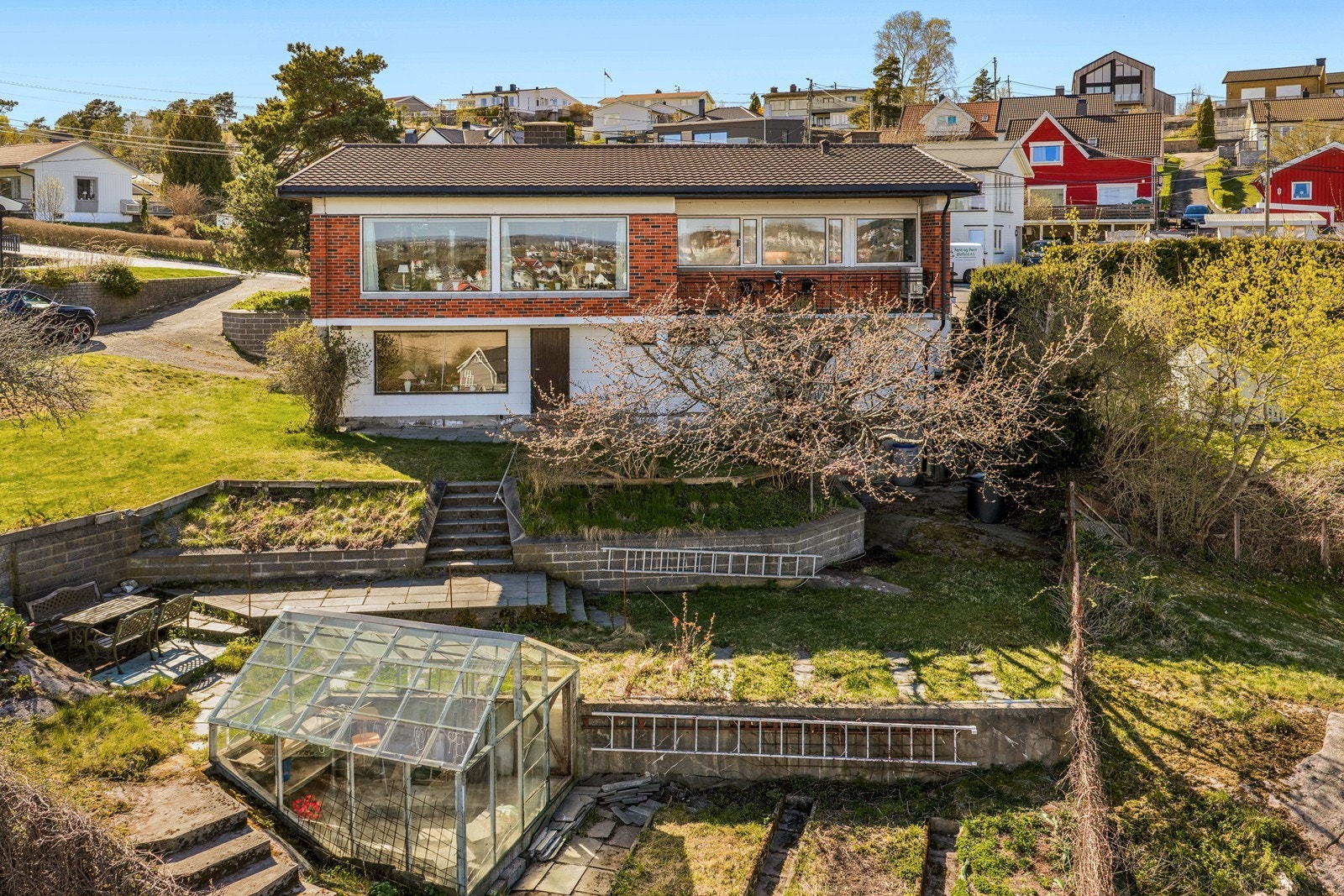 Tomten er opparbeidet på flere nivåer med grøntarealer, støttemurer og trapper i terrenget. Galleribilde