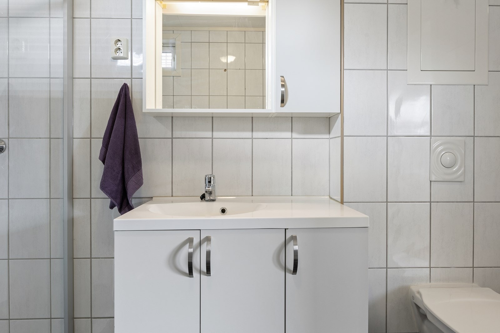 Baderomsinnredning med hvite, slette fronter, nedfelt servant og vegghengt toalett. Galleribilde