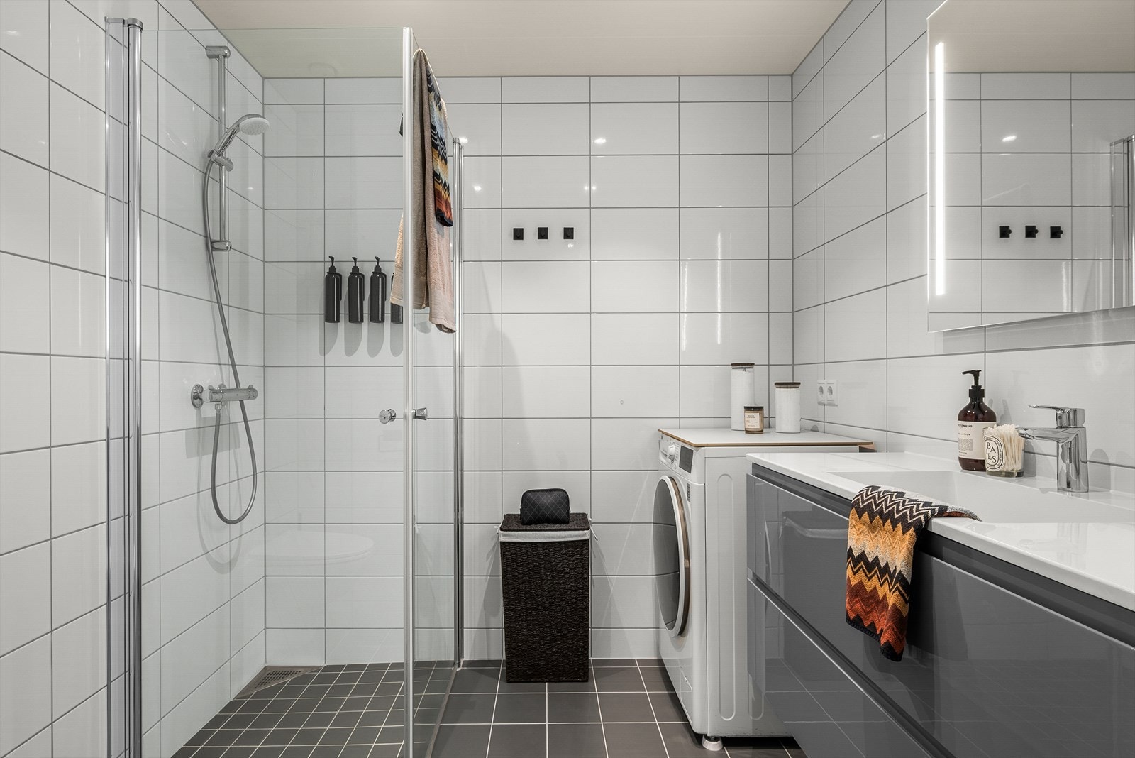 Flott flislagt bad på hele 5 m², med gode oppbevaringsmuligheter under vasken, opplegg for vaskemaskin og innfellbare dusjdører. Galleribilde