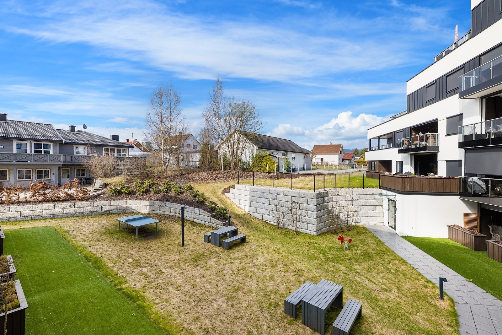 Tomten er opparbeidet med hellelagte internstier, gressplen og beplantninger. Galleribilde
