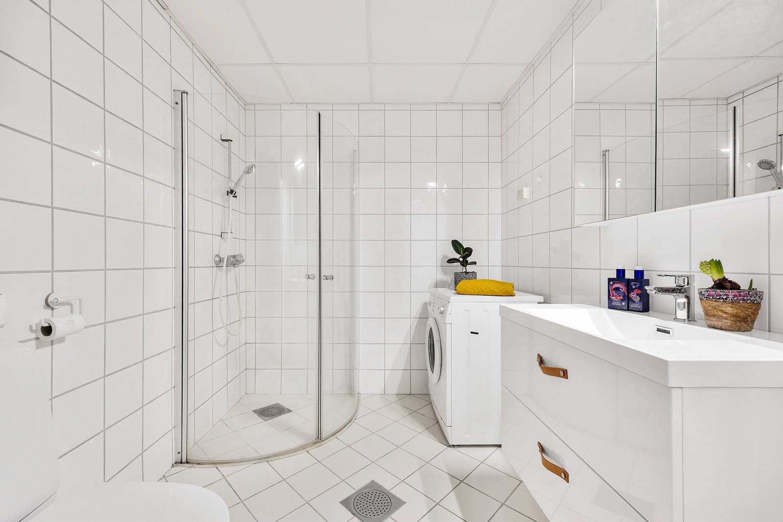 Rommet er helfliset og utstyrt med dusjhjørne med innfellbare glassdører, samt opplegg for vaskemaskin. Galleribilde