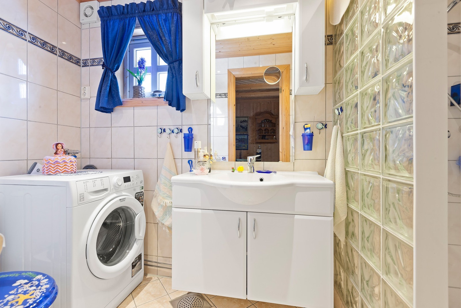 Badet har lys innredning med nedfelt servant med skap under, overskap og speil med lys over, dusjnisje, toalett samt opplegg for vaskemaskin. Varme i gulv. Galleribilde