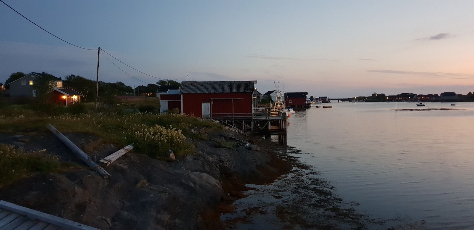 Tomten ligger inn mot den røde brygga. Det er dypt utenfor berget, og fin bunn. Bildet er tatt mot vest, på en sommerkveld. Galleribilde