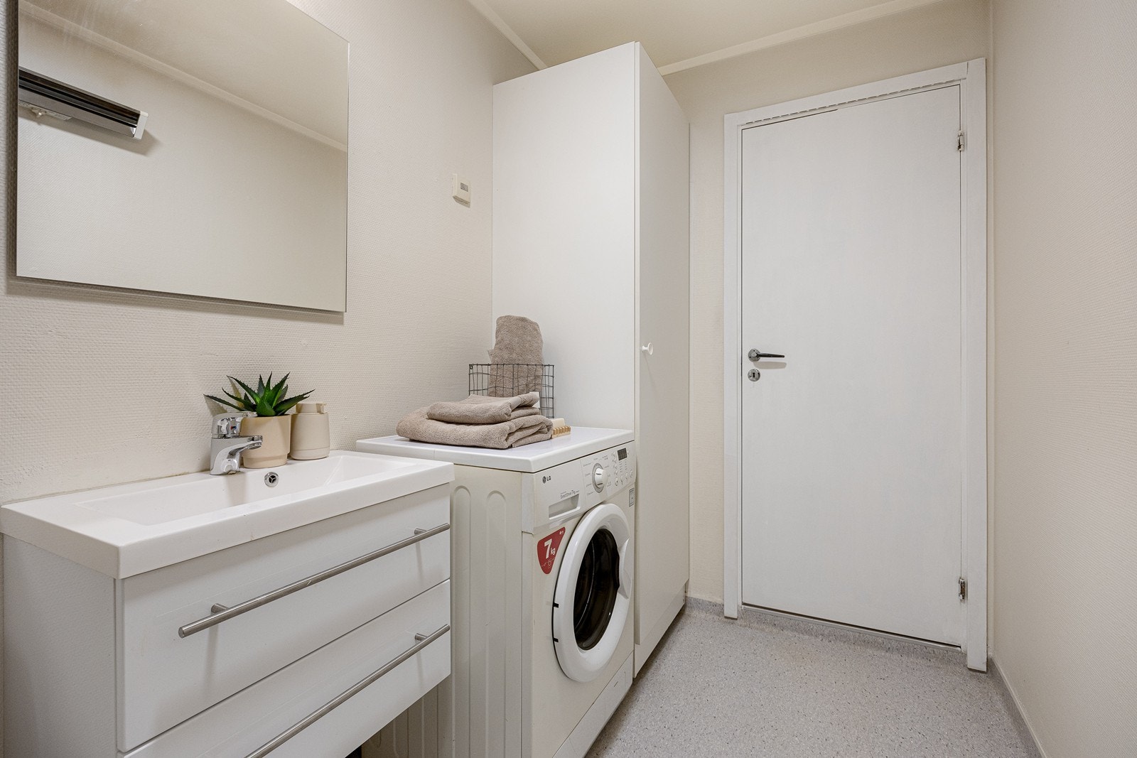 Videre har badet gulvmontert toalett, dusjkabinett med dører av herdet glass og opplegg for vaskemaskin. Galleribilde