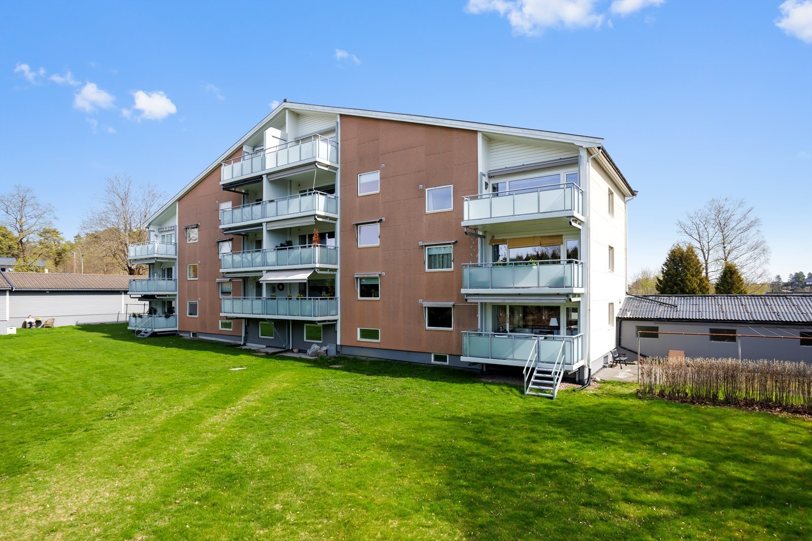 Fasaden presenterer et ryddig og innbydende ytre, med grønne fellesarealer rundt. Galleribilde