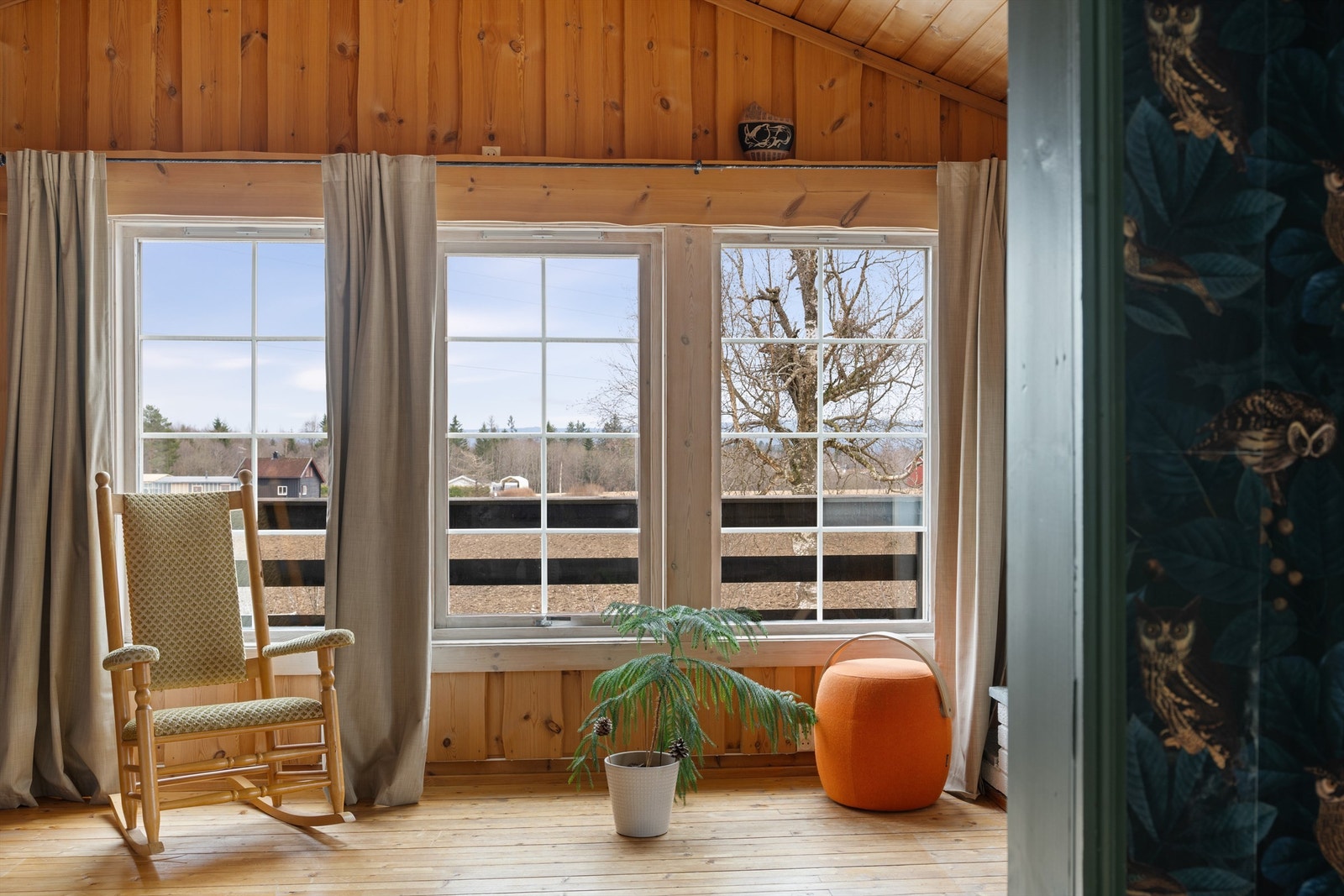 Store vindusflater i peisestuen slipper inn rikelig med dagslys og gir utsyn over eiendommen. Galleribilde