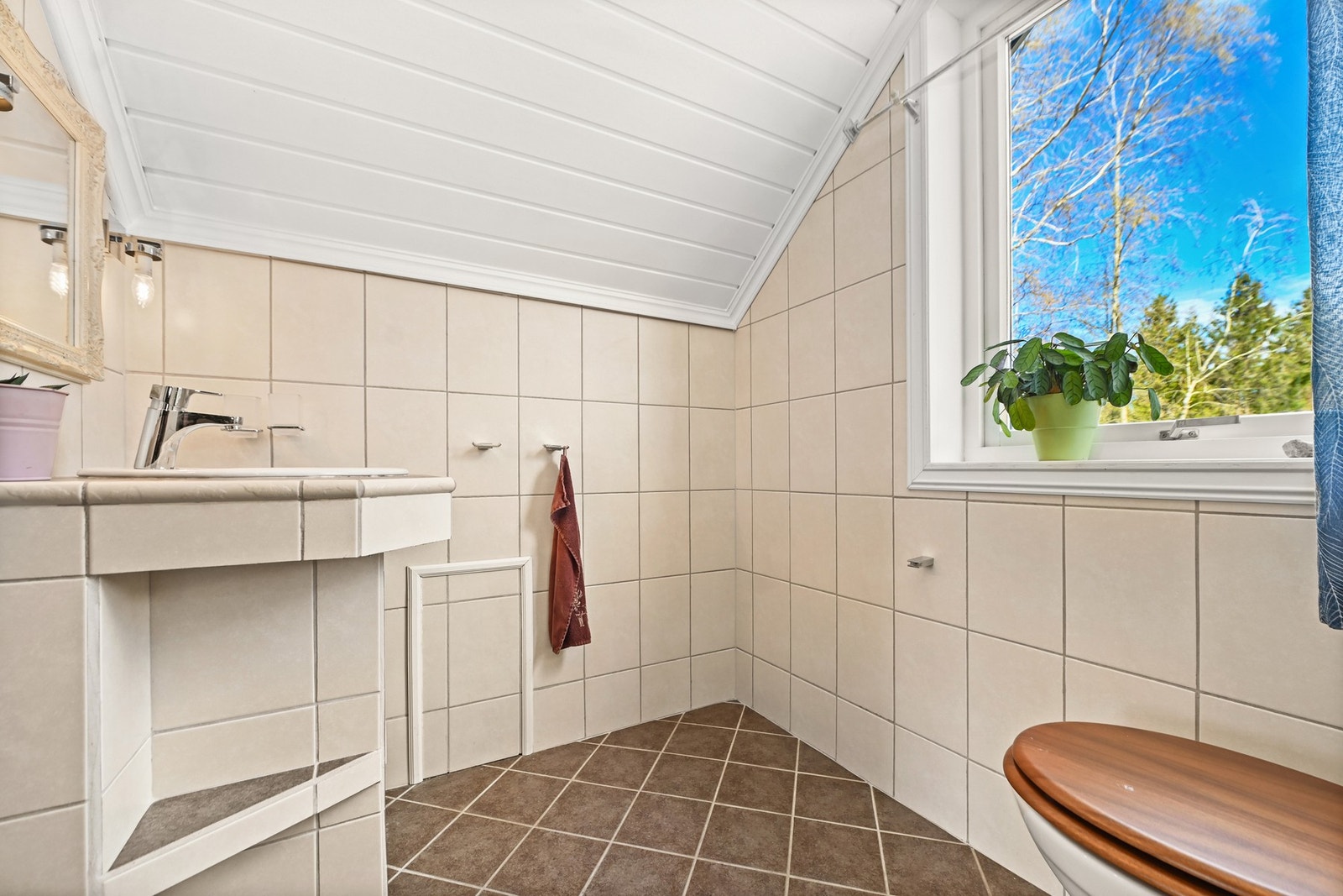 Flislagt bad med skråtak og vindu som slipper inn naturlig lys. Galleribilde