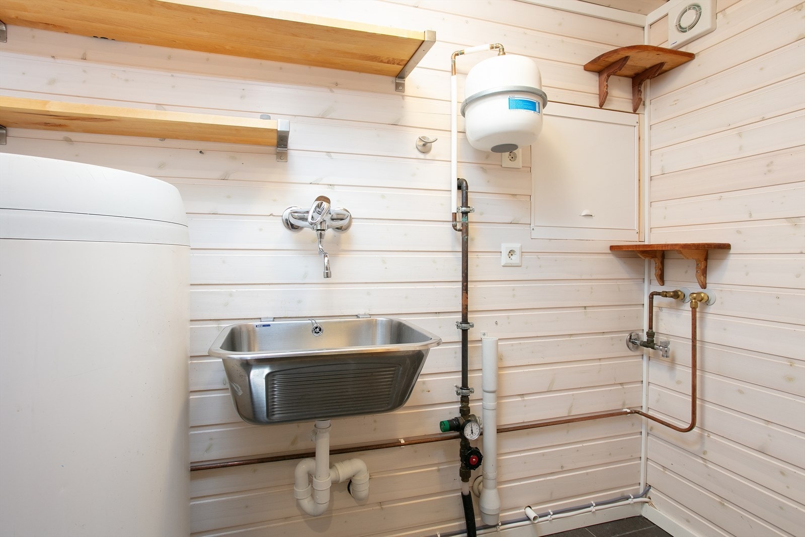 Praktisk vaskerom med fliser og varmekabler, opplegg for vaskemaskin og en 200-liters varmtvannsbereder. Galleribilde