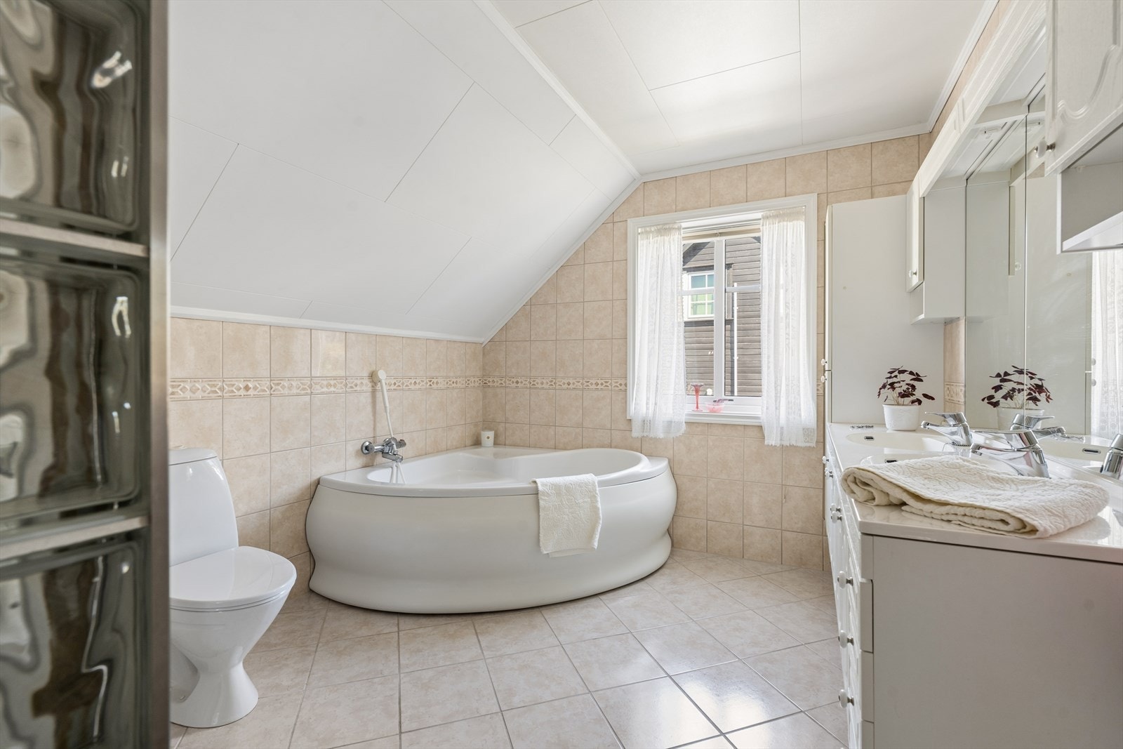 Baderommet har grunnbase fra byggeår, men er oppgradert med fliser i senere tid. Badet er i dag innredet med beige, sjatterte fliser på gulv og vegger og i har i tillegg varmekabler i gulvet. Galleribilde