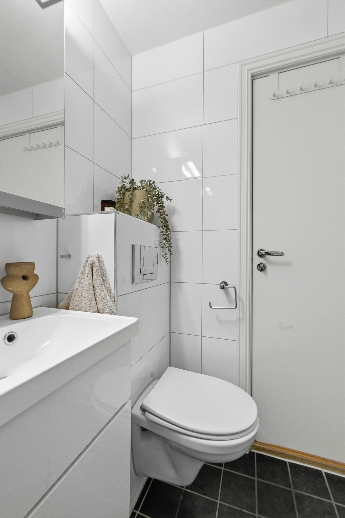 Badet er innredet med servant i innredning, dusjhjørne, vegghengt toalett og opplegg for vaskemaskin. Et funksjonelt og stilrent rom med gode løsninger for hverdagen. Galleribilde
