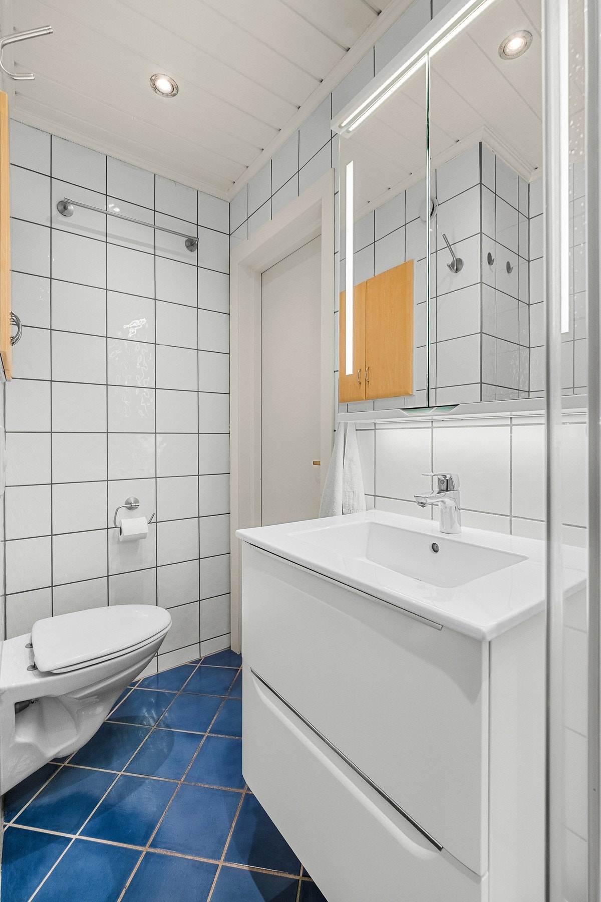 Badet er innredet med veggmontert toalett, servantinnredning og dusjkabinett Galleribilde