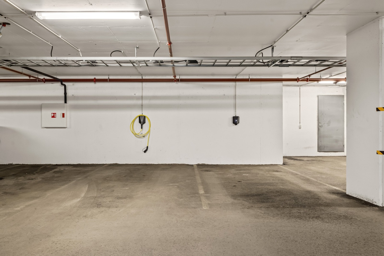 Parkeringsplass i garasjekjelleren med elbillader. Galleribilde