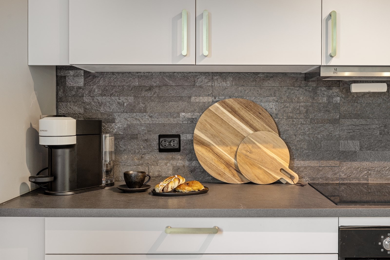 Benkeplate i laminat og flisimiterte plater på veggen mellom benk og overskap. Galleribilde