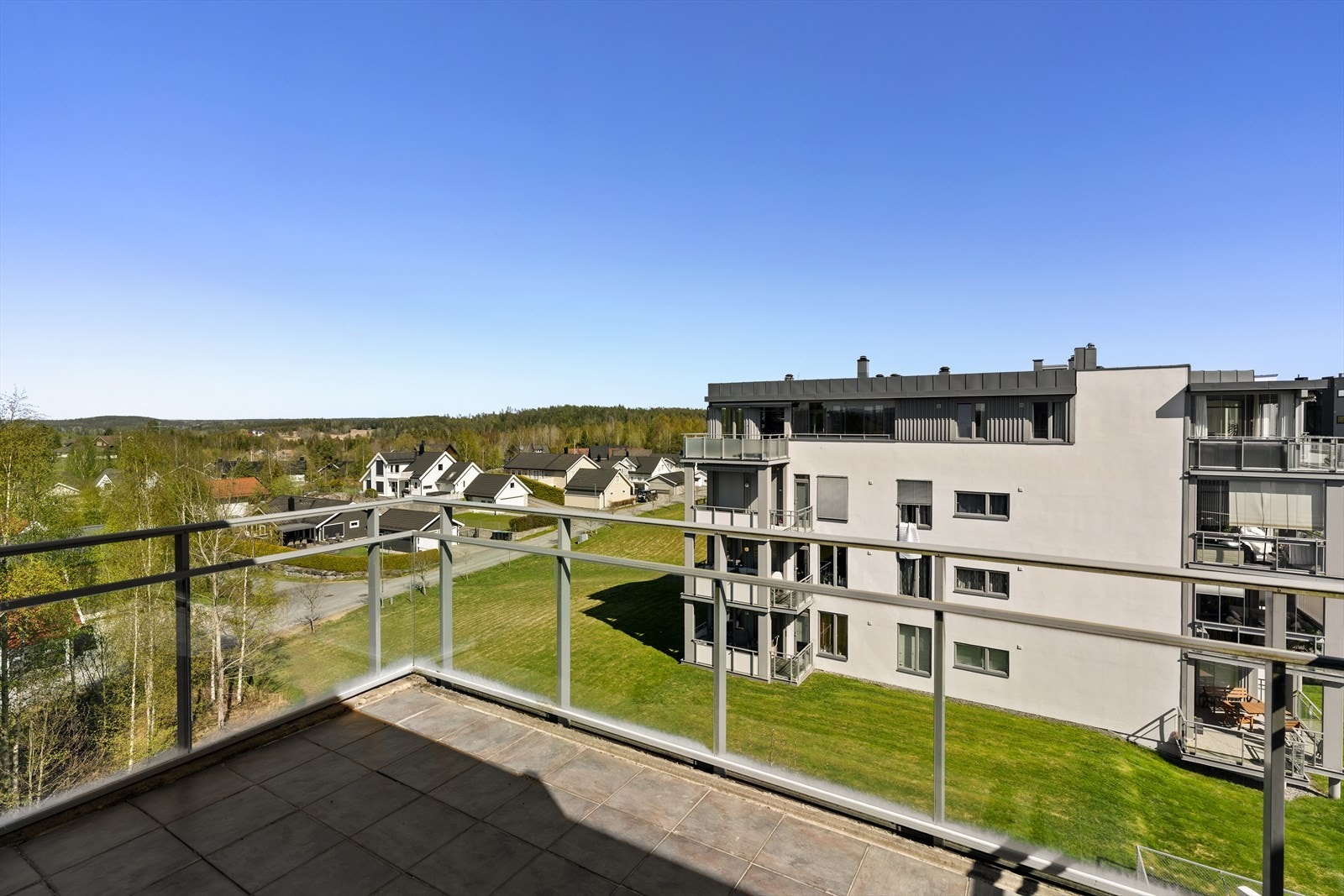Utsikt over de grønne fellesområdene fra den ene av leilighetens to balkonger. Galleribilde