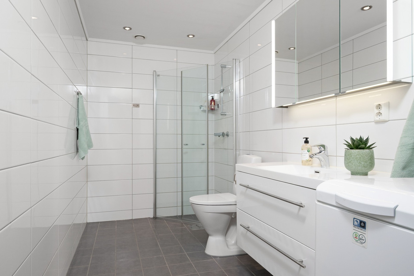 Badet er innredet med varmekabler, flis på vegg og malte plater på innvendig tak. Galleribilde
