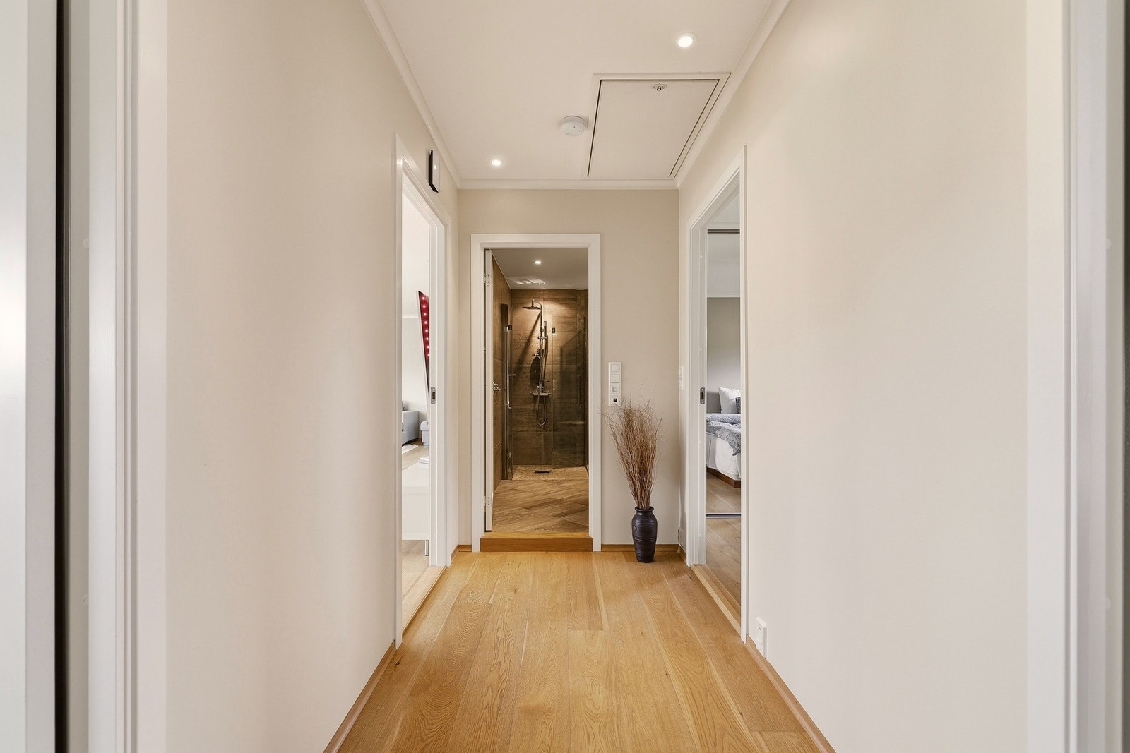 Bildet viser mellomgang i hoveddelen. Pent 1-stavs eikeparkettgulv, nymalte overflater og innfelte downlights i taket. Galleribilde