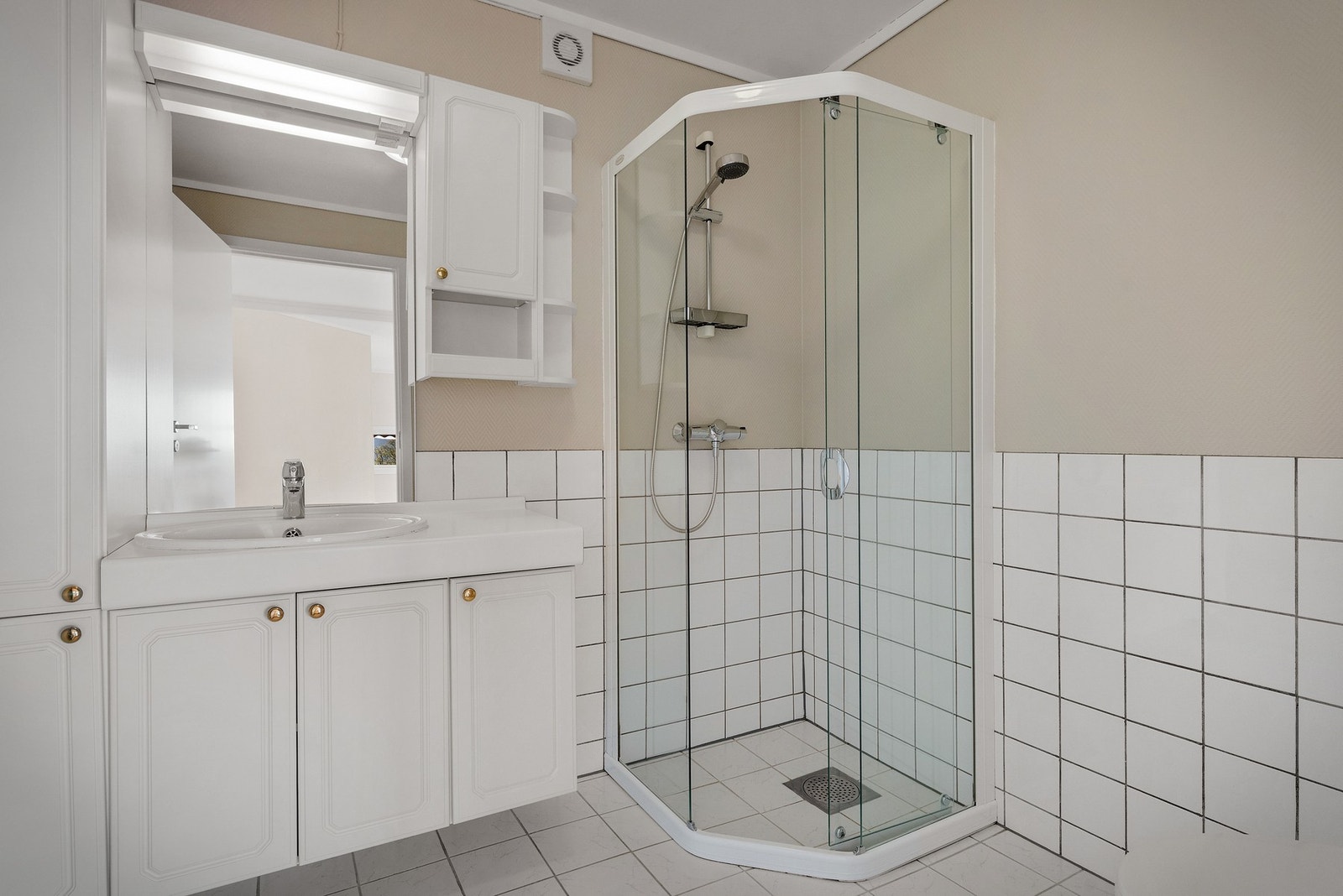- Badet er innredet med servant i møblement med speil og belysning, toalett og et buet dusjhjørne i glass med tilhørende dusjgarnityr - Galleribilde