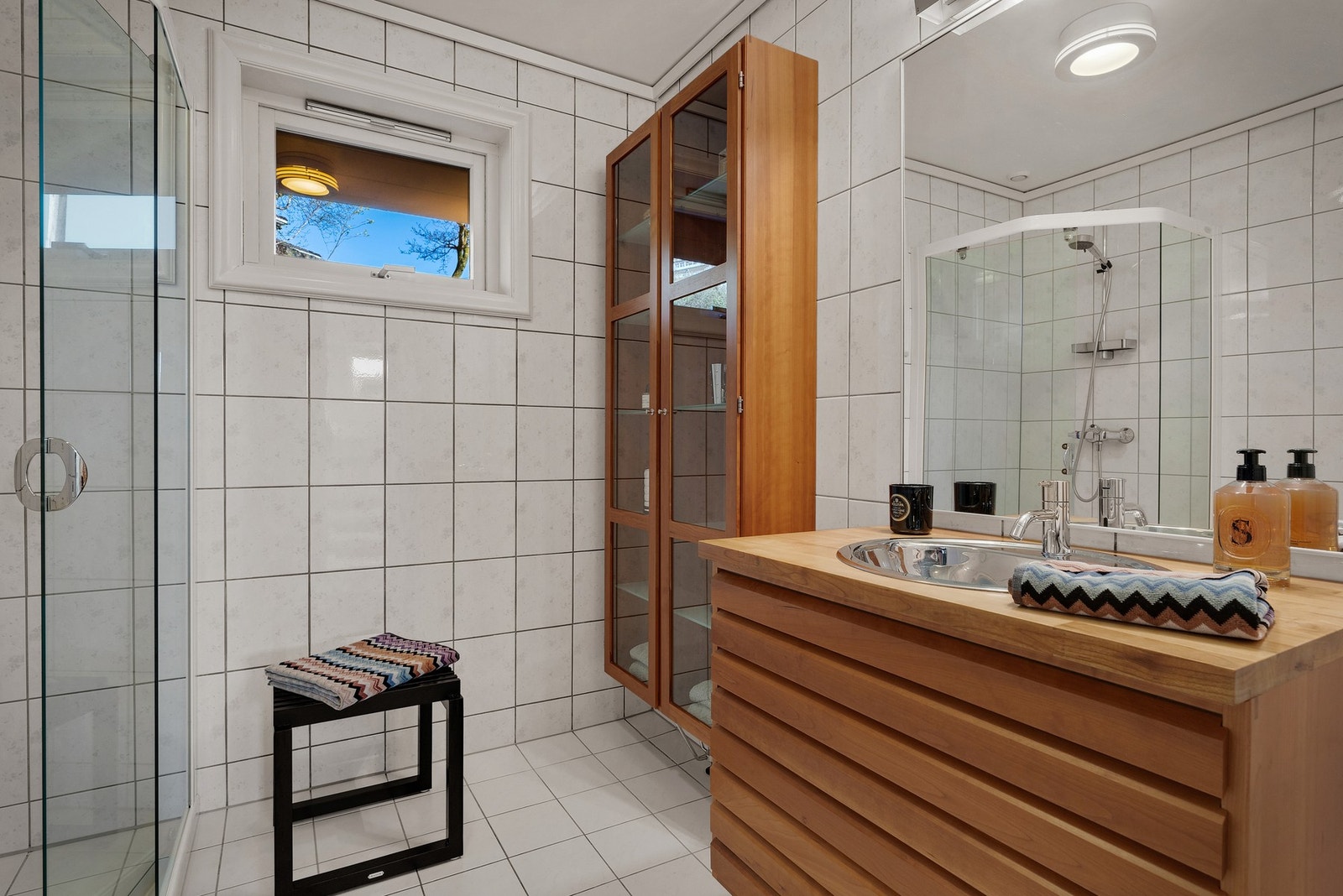 - Badet er innredet med servant i heltre møblement fra Unoform, speil med belysning, toalett og et buet dusjhjørne i glass med tilhørende dusjgarnityr - Galleribilde