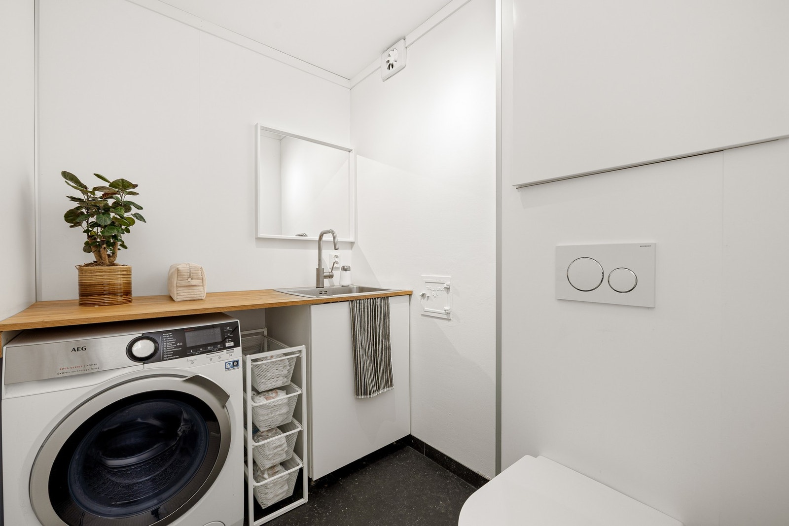 Praktisk vaskerom med opplegg for vaskemaskin. Laminatflis på gulv med gulvvarme. Galleribilde